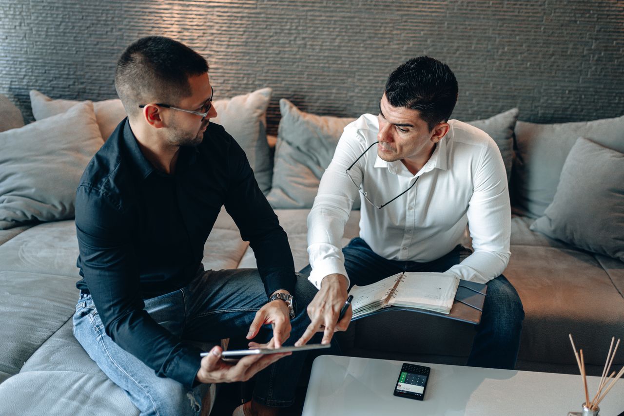 About Two men collaborating on a business project using a tablet in an office setting.